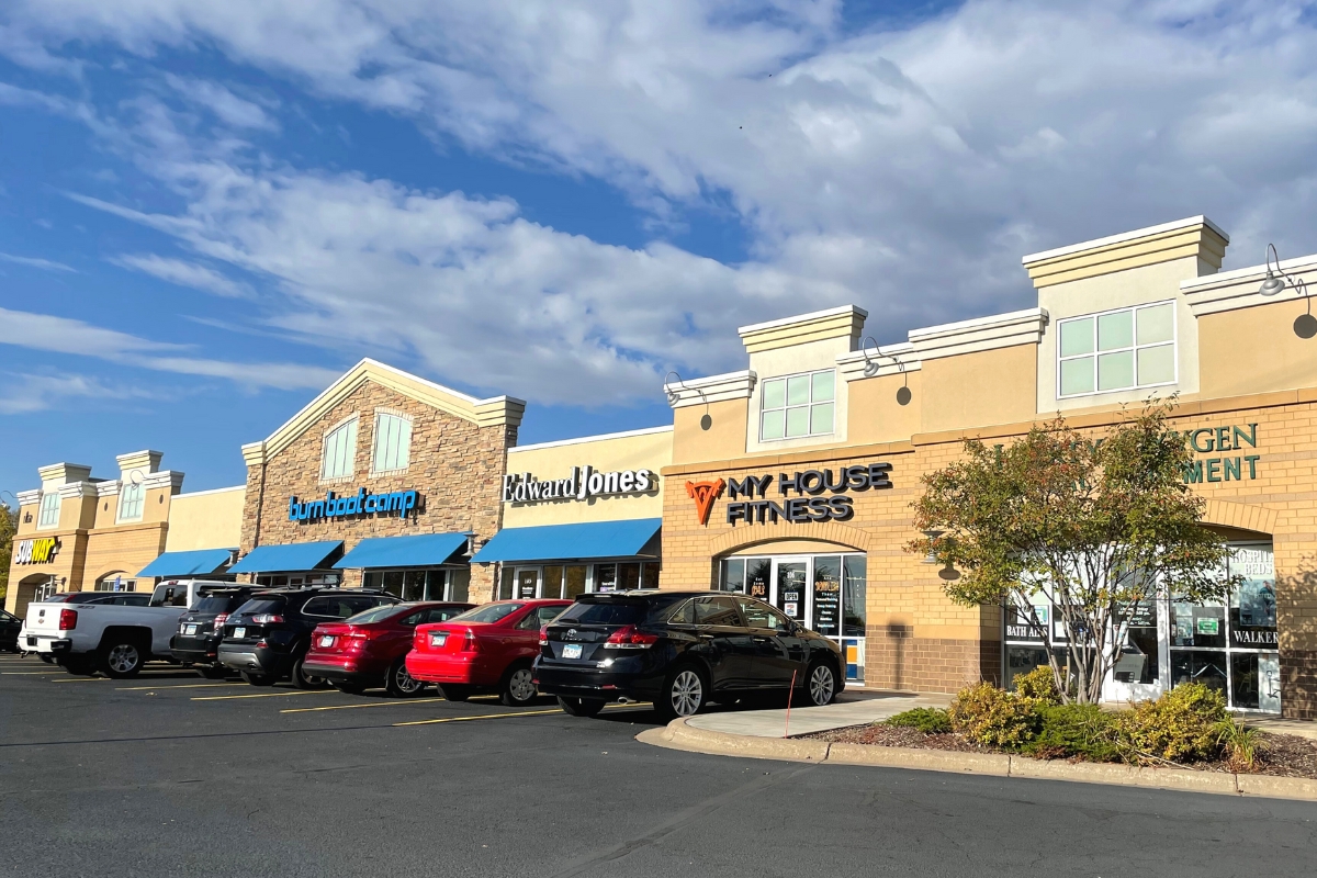 shopping center with blue awnings cars parked in front