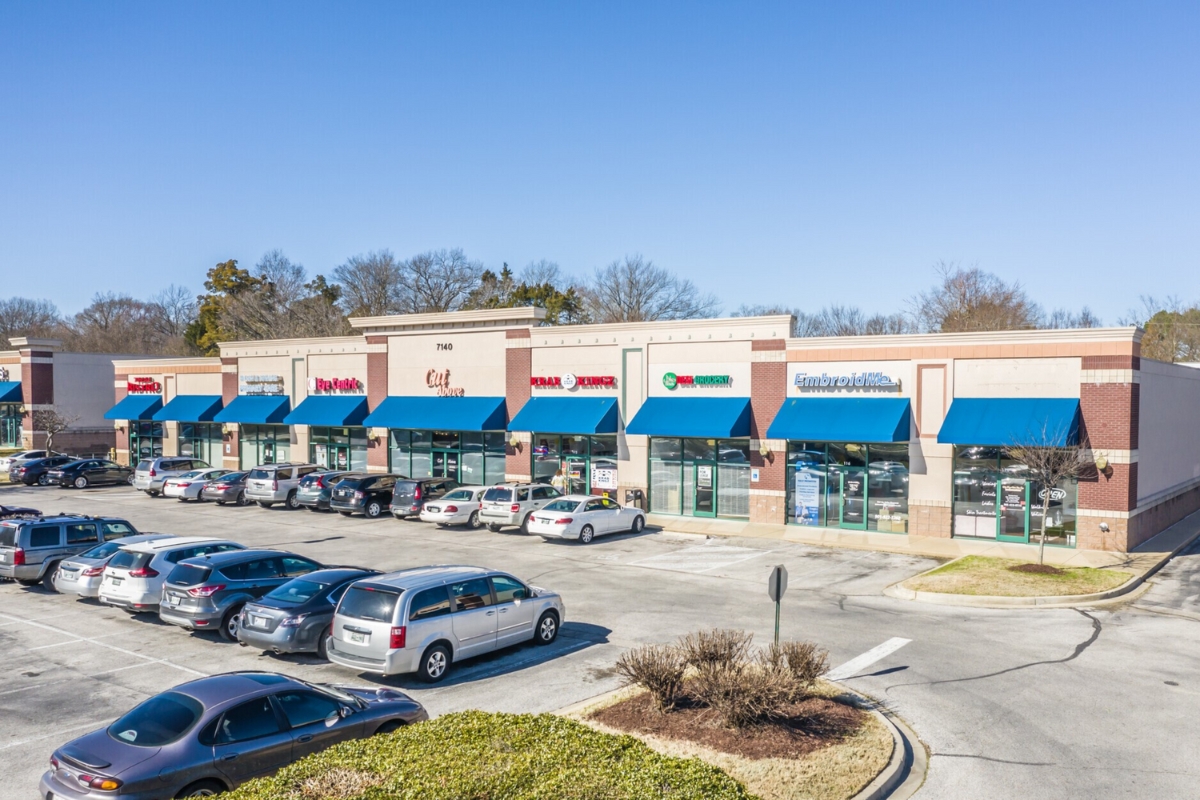 shopping center with blue awnings and cars parked in front