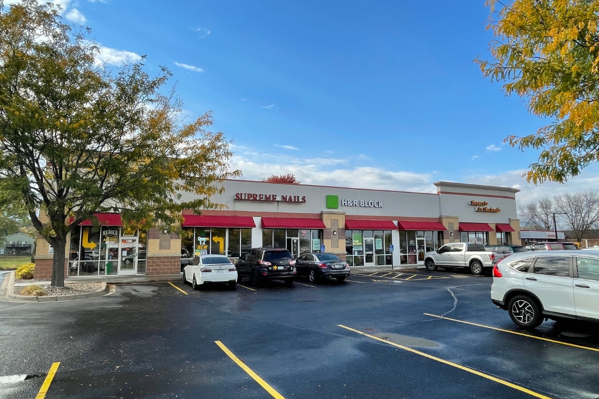 shopping center with red awnings and cars parked in front