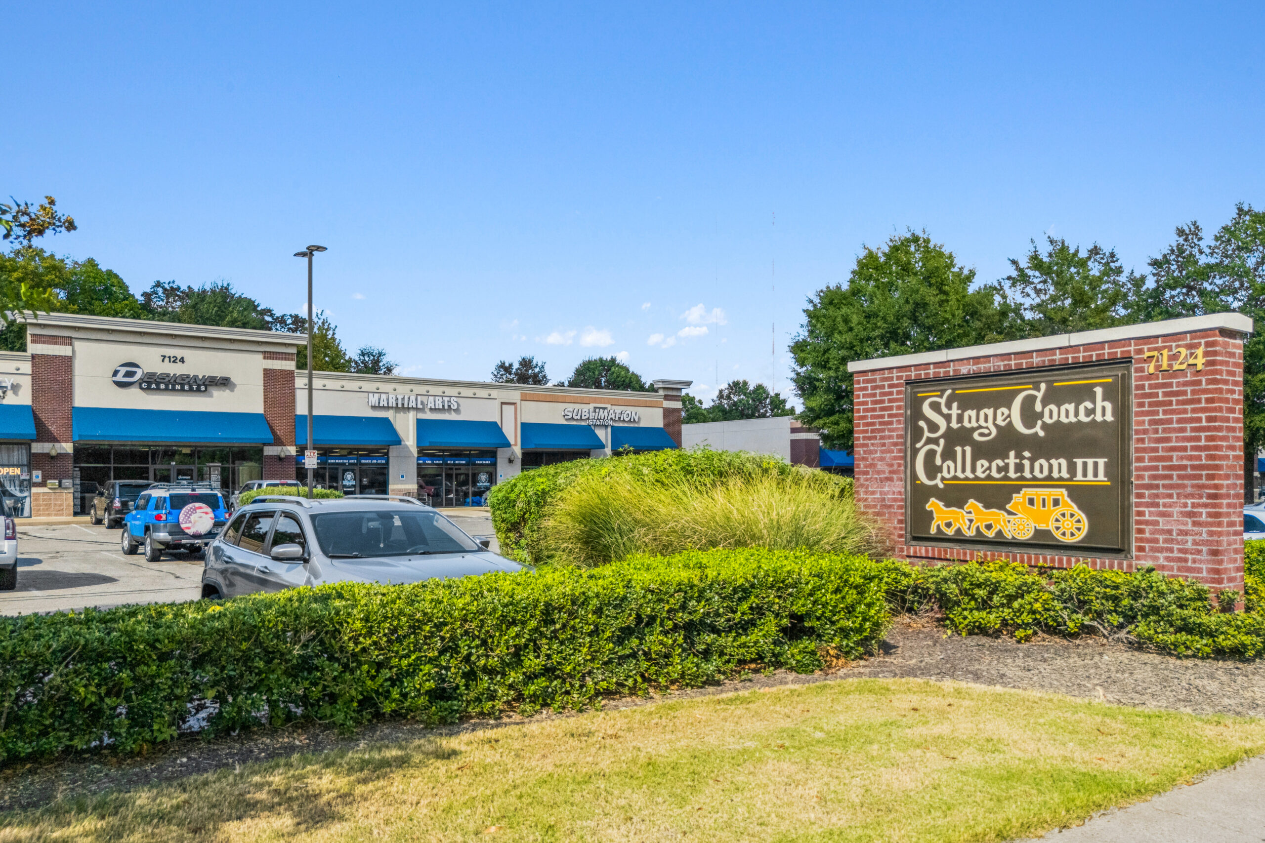 shopping center with blue awnings and cars parked in front