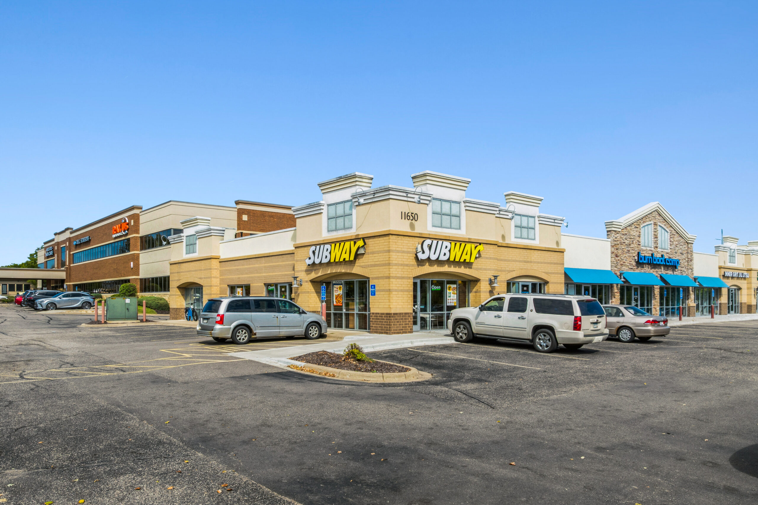 shopping center with blue awnings cars parked in front
